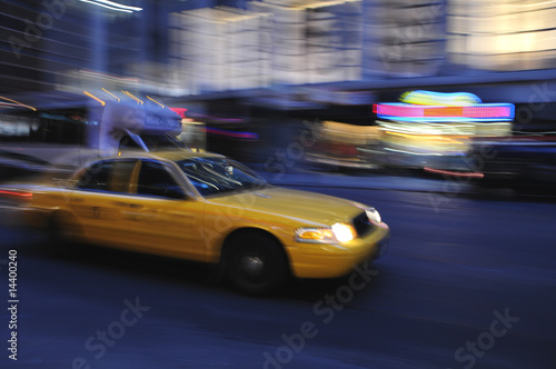 Taxi cab speeding down a city street at night