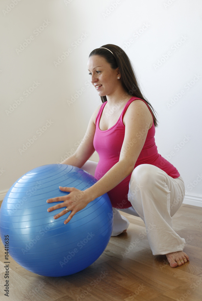 Young smiling pregnant woman doing squatting exercise Young smiling pregnant woman doing squatting exercise