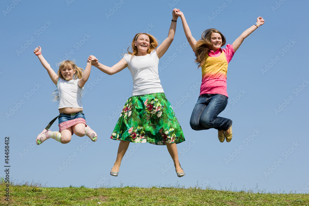 Happy Mother and two daughter jumping on green meadow Happy Mother and two daughter jumping on green meadow