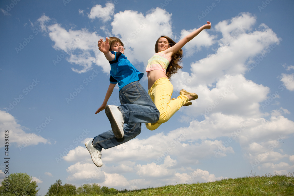 Happy teens - jumping under blue sky. Soft focus. Focus on eyes