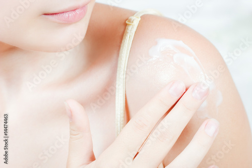 Woman applying cream on her shoulder