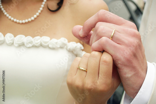 Young couple holding hands, their wedding rings are seeing