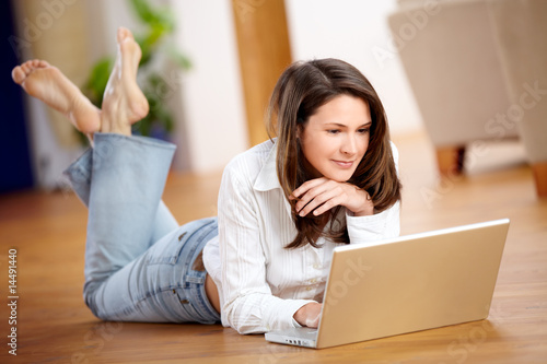 Junge Frau mit Laptop am Boden liegend photo