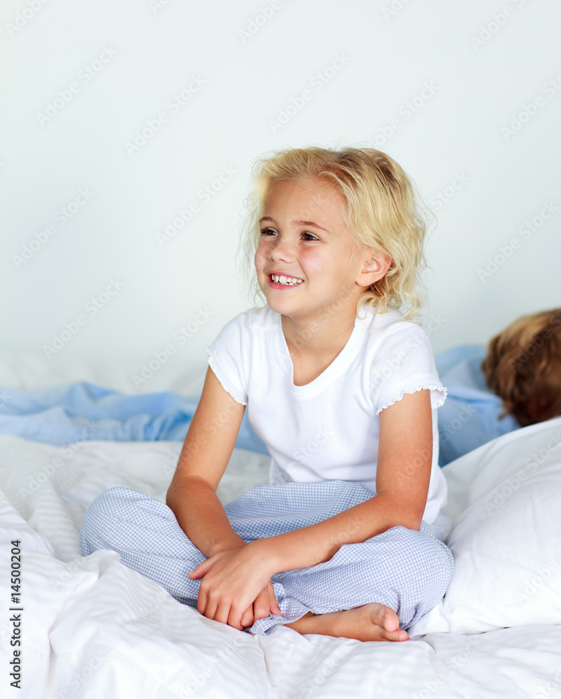 Fototapeta premium Little girl in bed smiling while her brother is sleeping