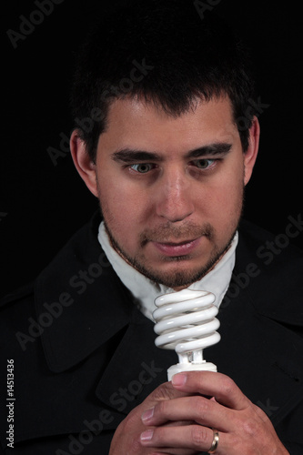 male portrait staring at new light bulb isolated on black