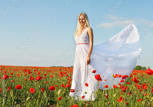 young beautiful woman in white dress on poppy field background