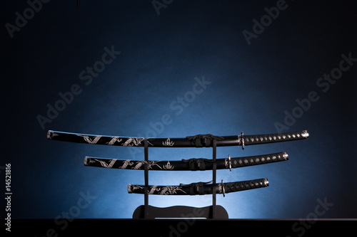 Katana, wakizashi and tanto on blue background. Copy space.