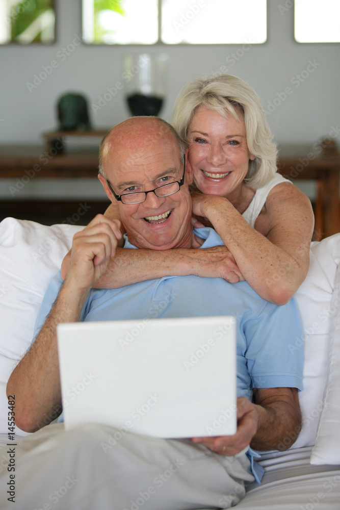 Obraz premium elderly couple smiling with laptop