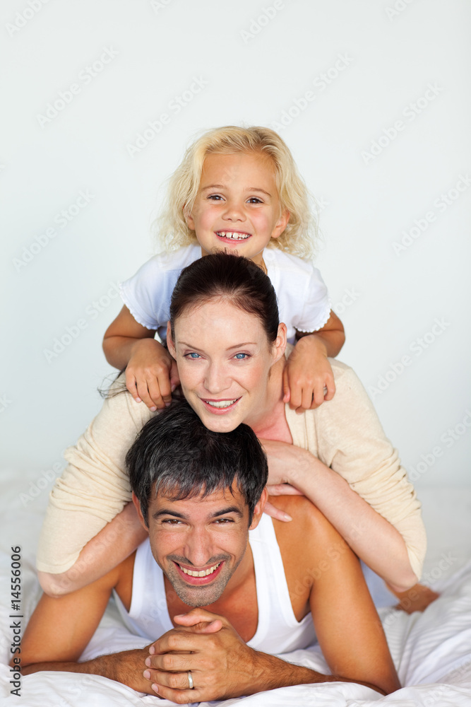 Father, mother and daughter playing in bed