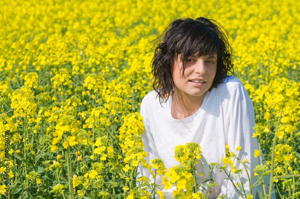Fototapeta premium Relaxing girl in the rapeseed yellow field