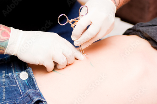 man wearing gloves making a navel piercing