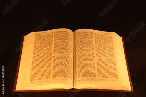 The Holy Bible open under candle light.