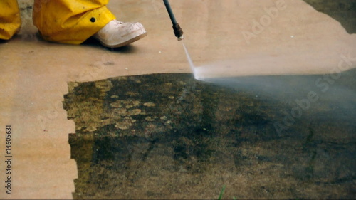 Pressure cleaning - worker cleaning a dirty old driveway