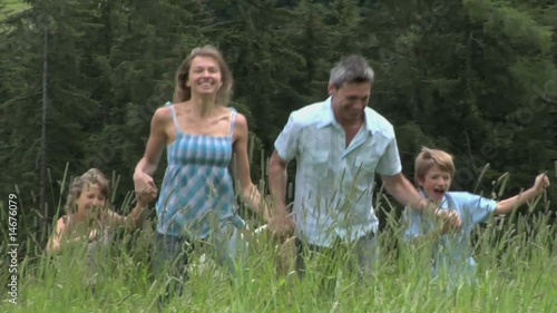 famiglia felice corre nei prati di montagna photo