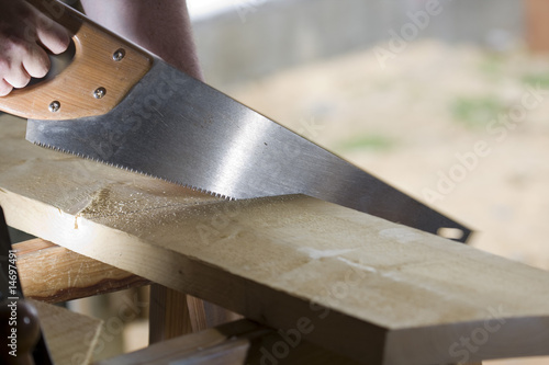 carpenter cuts a plank with a saw