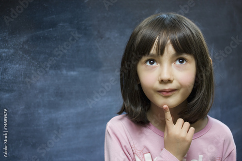 Adorable schoolgirl stay near school blackboard.