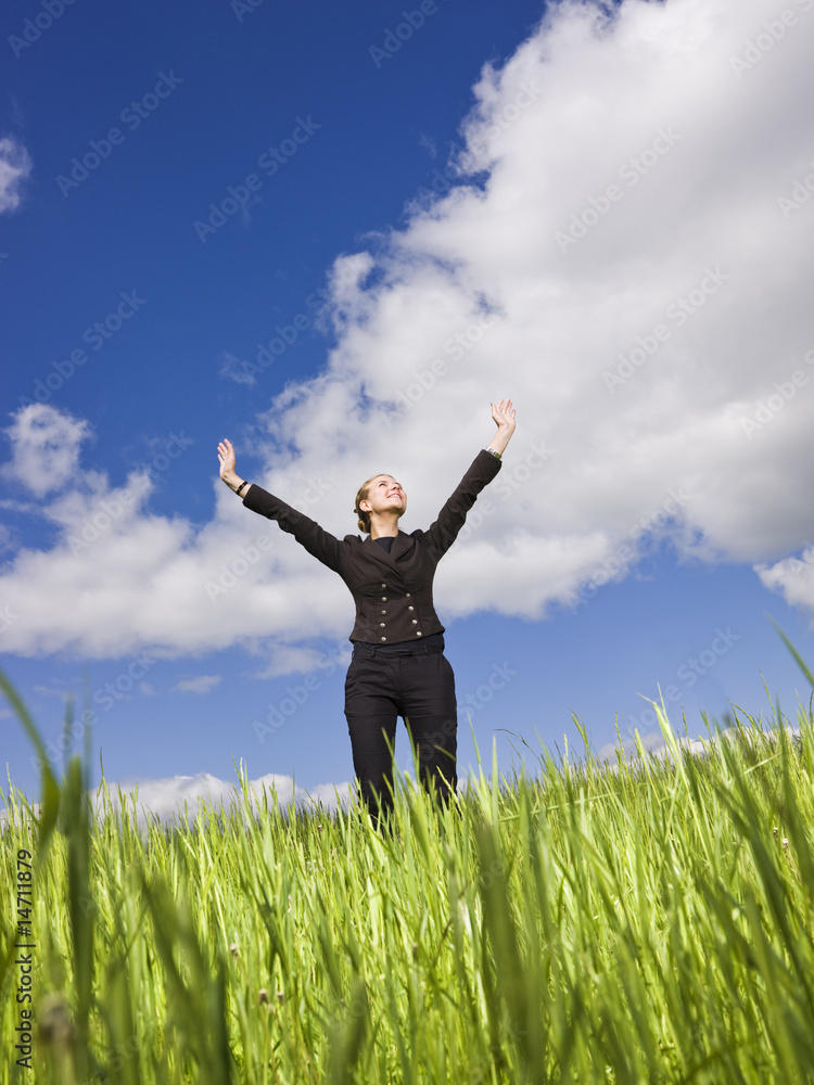 Young woman standing in the grass towards blue sky Young woman standing in the grass towards blue sky