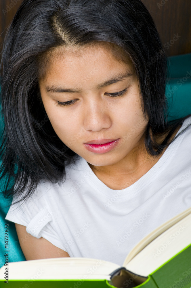 beautiful young asian woman reading a book in bed