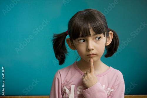 Pensive schoolgirl stay near school blackboard.