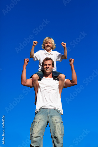 Strong son sitting on his father's shoulders