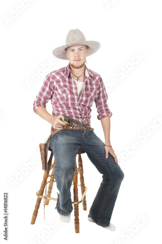 young bearded cowboy sitting on stool with pistol drawn