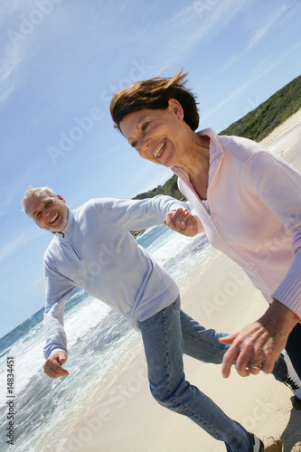 Portrait d'un couple de seniors courant au bord de la plage