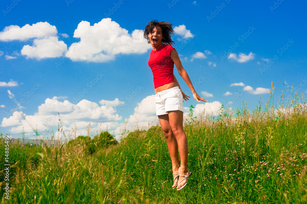 Happy young woman jumping in a field Happy young woman jumping in a field