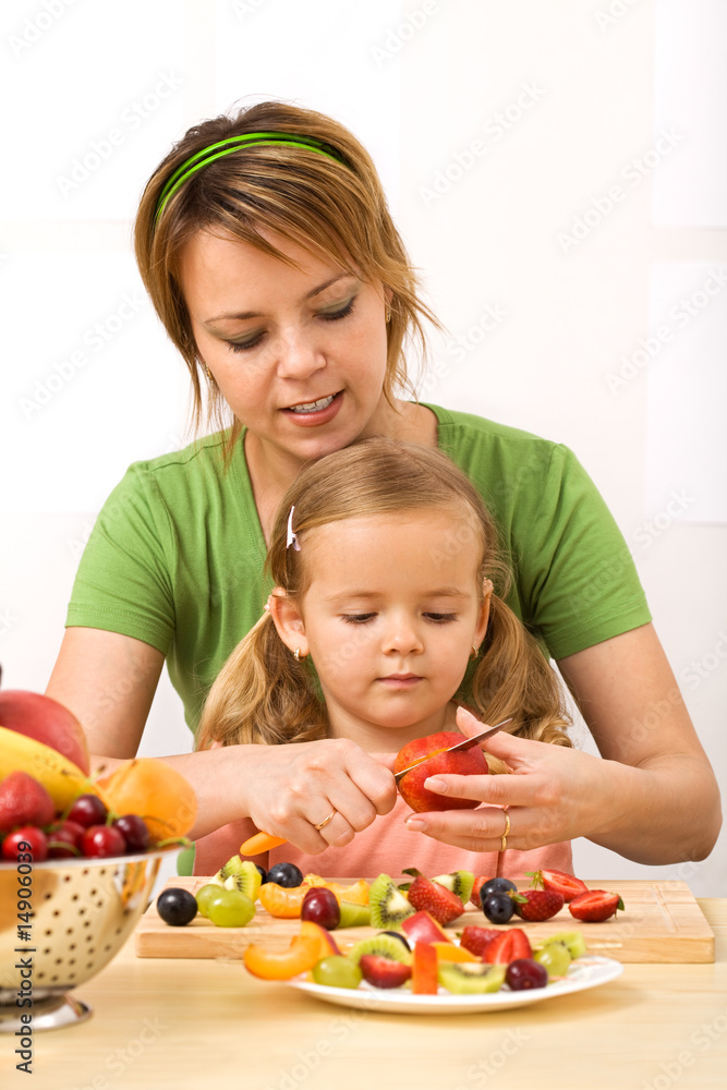 Woman and little girl slicing fruits Woman and little girl slicing fruits