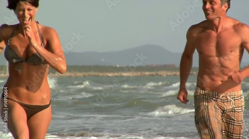 Uomo insegue per gioco una donna al mare di corsa photo