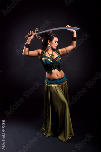 Attractive bellydancer in tribal costume and holding sword