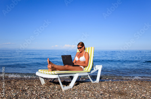 Sexy beautiful woman in bikini using laptop at the beach © Rogatnev