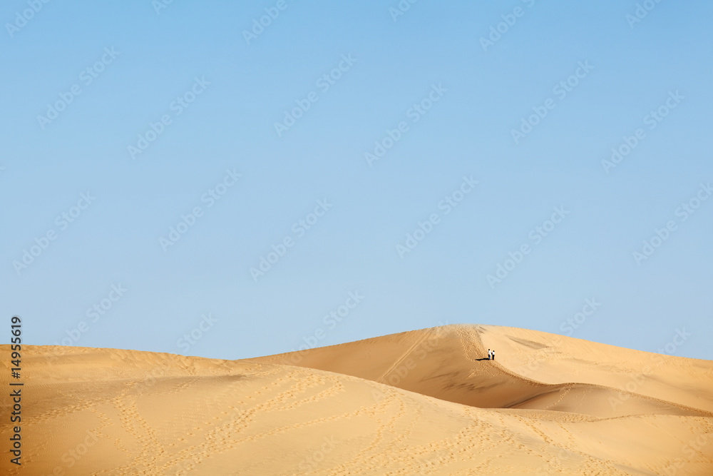 two people walking in desert dunes