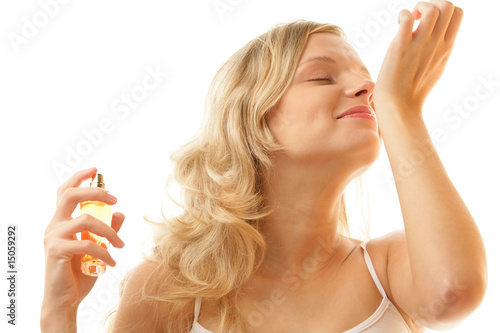 Woman holding perfume bottle smelling her wrist