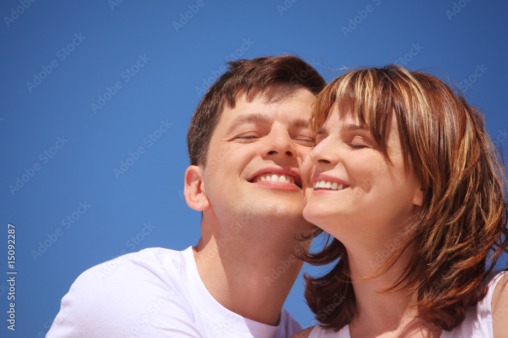 attractive pair against blue sky, touching by cheeks. attractive pair against blue sky, touching by cheeks.