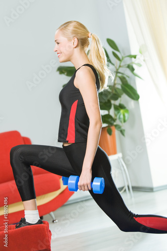 Young woman doing exercises with dumbbells at home