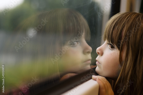 Little girl looking through window photo