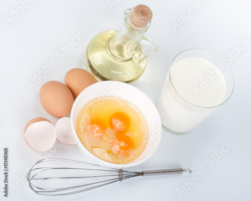 Eggs, oil, cup of milk and whisk