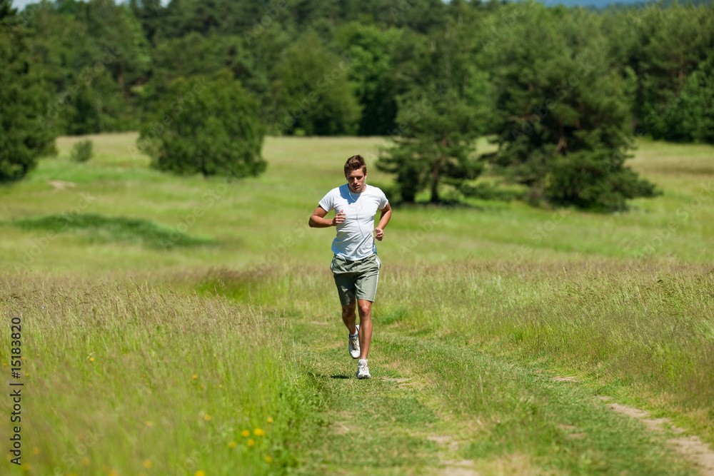 Young man with headphones jogging in a meadow Young man with headphones jogging in a meadow