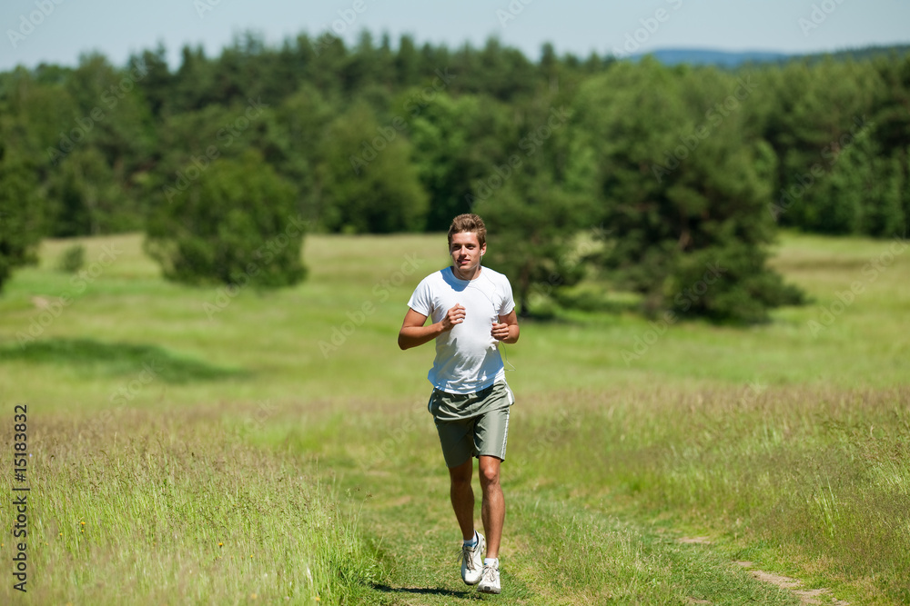 Young man with headphones jogging in a meadow Young man with headphones jogging in a meadow