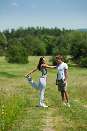 Man and woman stretching in a meadow