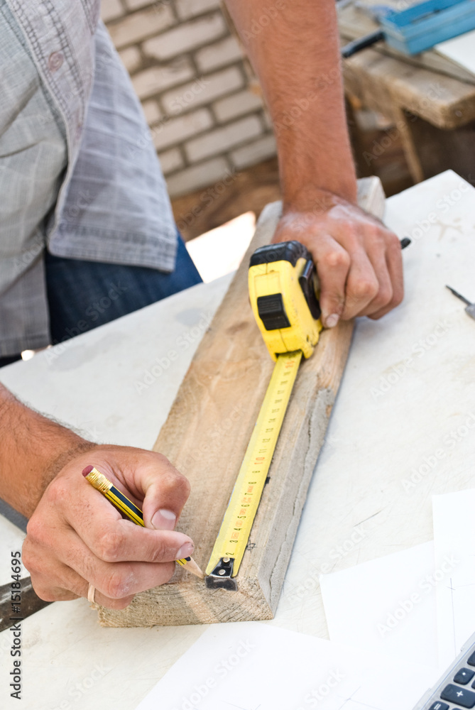 A woodworker measures the mark for his cut A woodworker measures the mark for his cut
