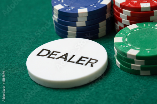 Dealer button and poker chips on a green surface.