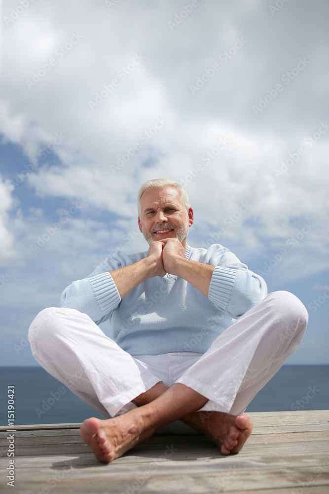 Homme senior assis par terre en bord de mer Stock Photo | Adobe Stock