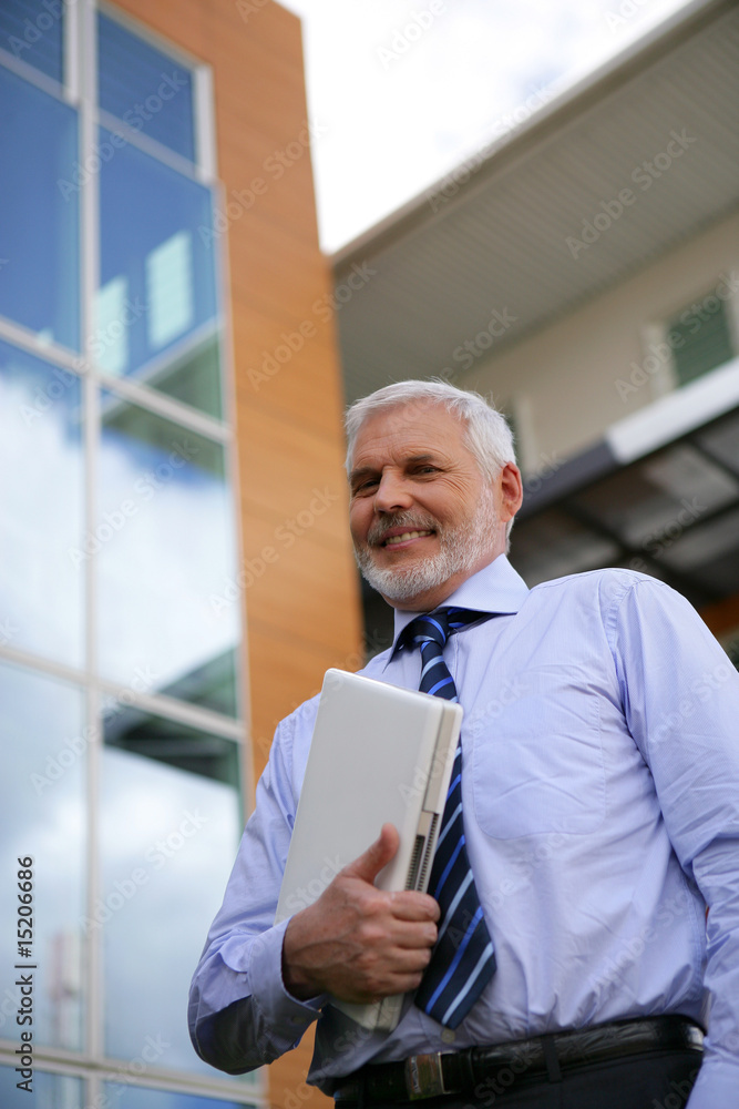 Homme senior en costume avec ordinateur portable sous le bras Homme senior en costume avec ordinateur portable sous le bras