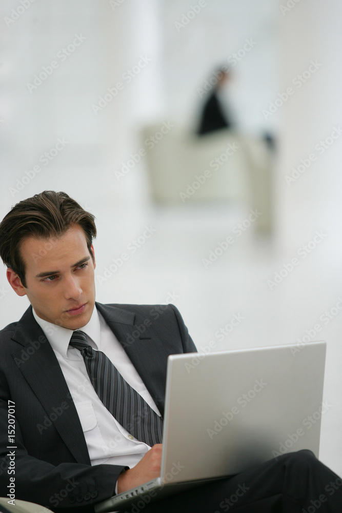 Jeune cadre dynamique assis devant un ordinateur portable Jeune cadre dynamique assis devant un ordinateur portable