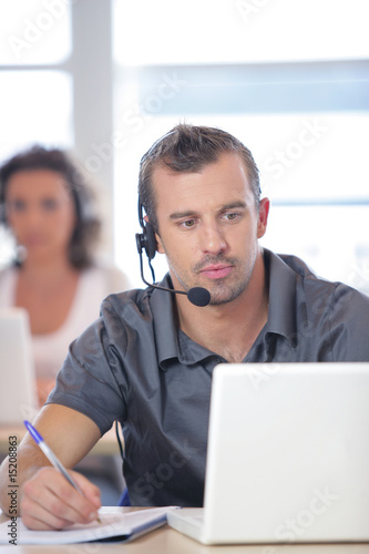 Tableau sur toile Homme assis devant un ordinateur portable avec un micro-casque