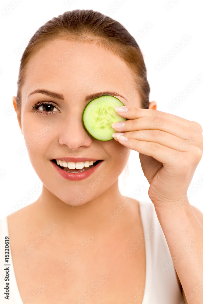 Woman holding slice of cucumber over eye Woman holding slice of cucumber over eye