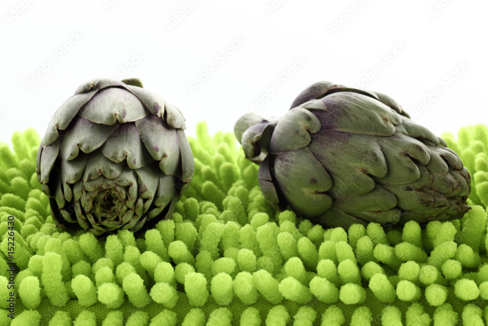Obraz premium Miniartischocken auf neongruenem Kissen