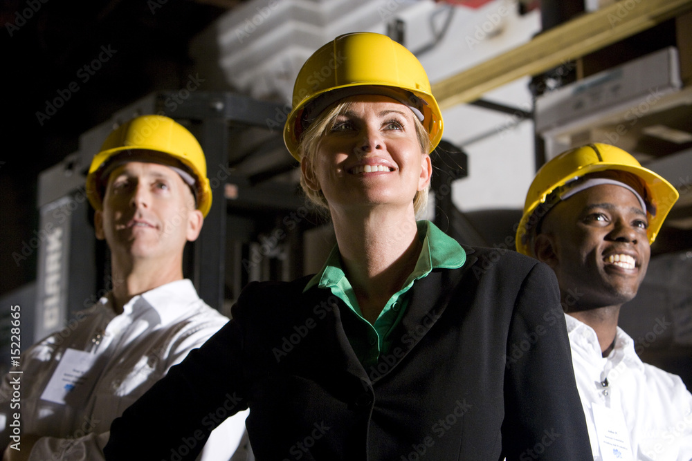 Office workers in storage warehouse wearing hard hats Office workers in storage warehouse wearing hard hats