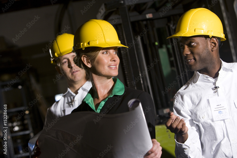 Office workers in storage warehouse wearing hard hats Office workers in storage warehouse wearing hard hats